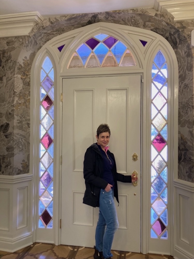 Woman stands by door with stained glass windows