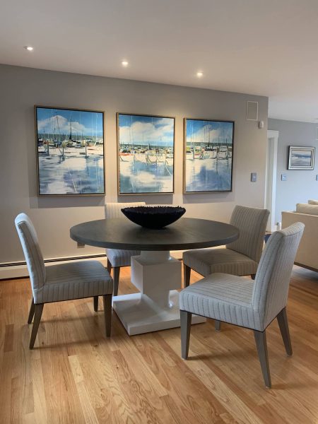 Dining table with three sailboat paintings on wall
