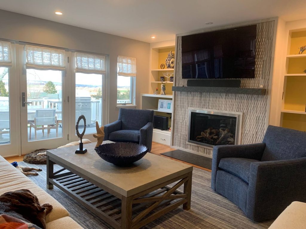 Coastal living room with coffee table, chairs, fireplace, and TV