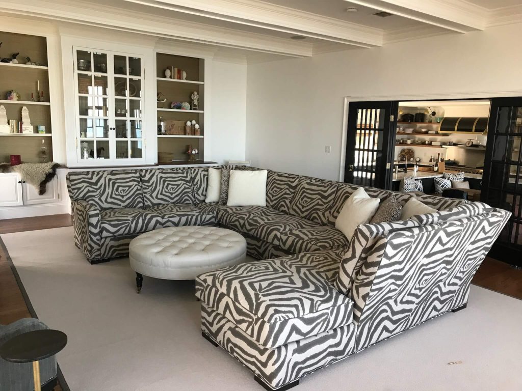 Living room with black and white patterned sectional and round white ottoman