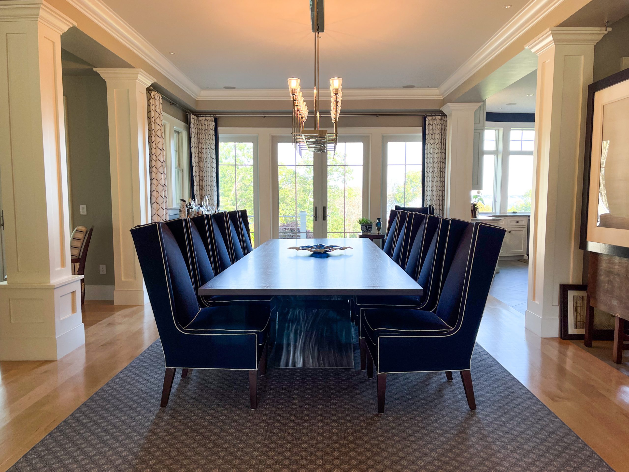 A dining room with a large rectangular table surrounded by high armchairs upholstered in Navy blue.