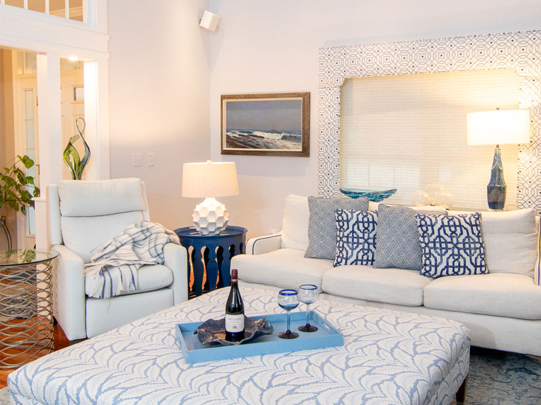 A light and bright living room furnished in soft white with blue accents.
